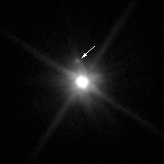 Makemake y su satélite (indicado por la flecha) vistos por el telescopio espacial Hubble