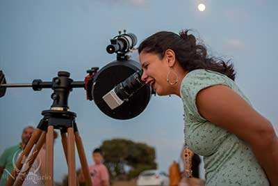 Chica observando por telescopio perseidas